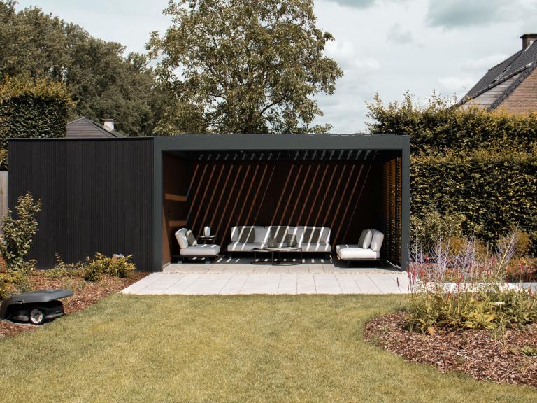 Renson Camargue terrasoverkapping geplaatst door Demaeght zonwering te Dilbeek. Een aluminium pergola gecombineerd met een houten tuinberging met zwart gelakte houten profielen. Combo tussen berging en outdoor living. Design architectuur tuin terras inspiratie offerte West-vlaanderen Oost-vlaanderen Deinze Kortrijk Tielt Roeselare Brugge Oudenaarde Kluisbergen Ronse Dilbeek Brussel Leuven