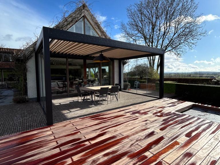 Renson Camargue lamellendak geplaatst door Demaeght zonwering te Doornik. Een aluminium pergola gemonteerd aan de woning. Schuifglas en geïntegreerde zonwering. Ook led-verlichting alsook een Lineo Fix lamel met een Heatsail verwarming eraan. Deinze Waregem Kortrijk Ronse Kluisbergen. Vraag hier uw vrijblijvende offerte op maat.